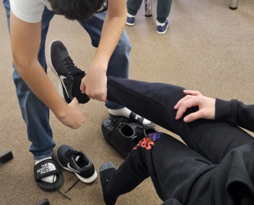 Tom pomáhá obout boty spolužákovi