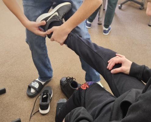 Tom pomáhá obout boty spolužákovi