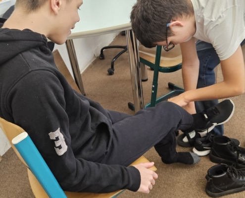 Tom pomáhá obout boty spolužákovi