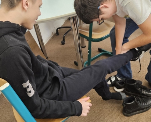 Tom pomáhá obout boty spolužákovi